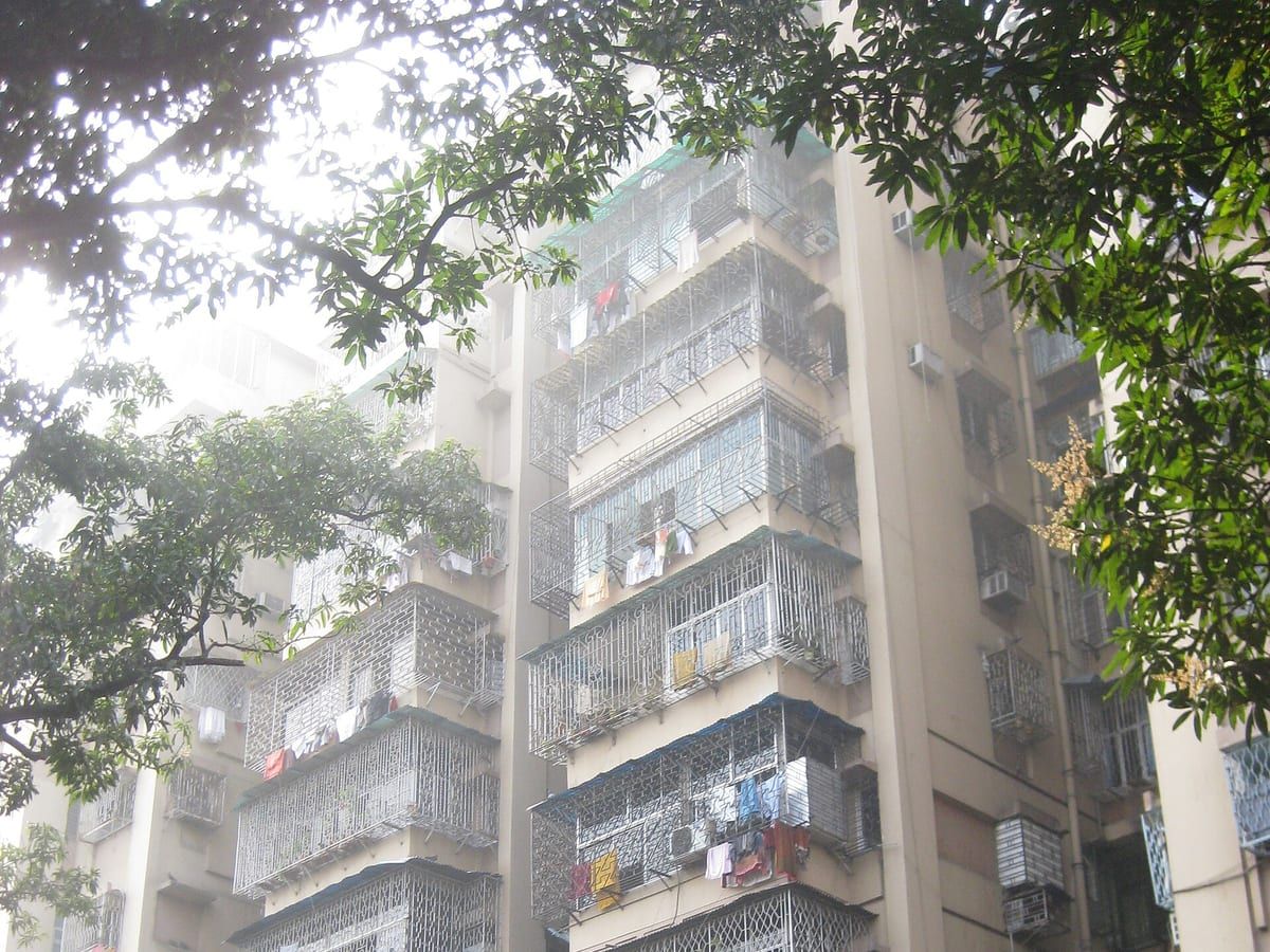 Four-storey residential block with projecting balconies and a mature tree at the kerb. Stand-in photograph for Tapati in Mukundapur.