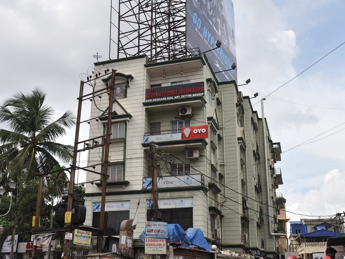 Street elevation of a mid-rise residential building with shopfronts at ground level. Stand-in photograph for Rituparna in Sonarpur.